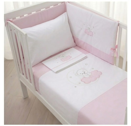 Pink teddy bear duvet set with padded bumper installed in a white wooden baby crib.