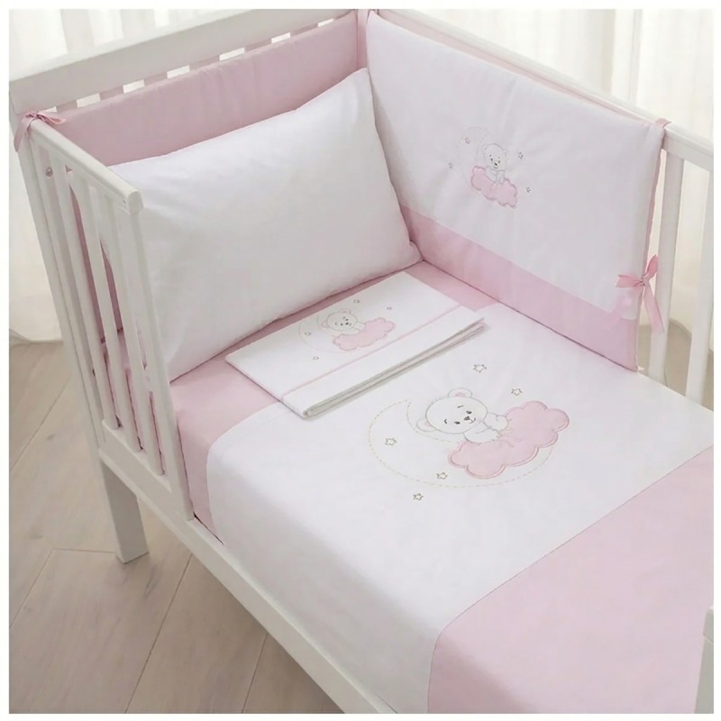 Pink teddy bear duvet set with padded bumper installed in a white wooden baby crib.