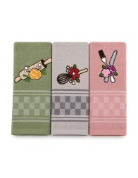 Set strofinacci cucina in cotone e spugna leggermente aperti su piano cucina con dettagli ricamati e colori pastello.